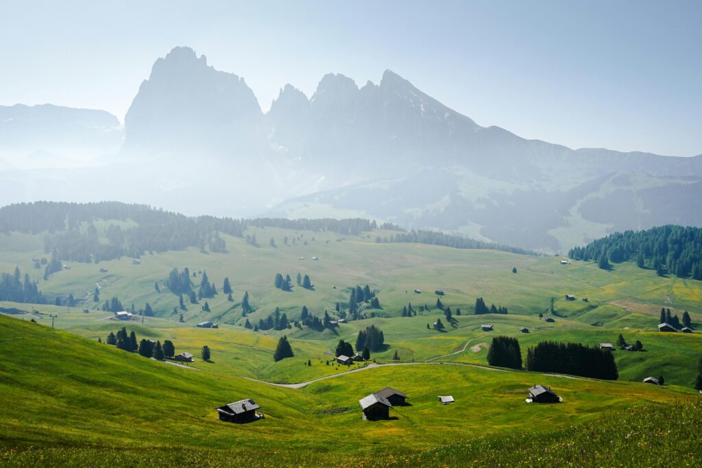 Stunning panoramic view of the Dolomites with lush green meadows and scattered houses in Italy.