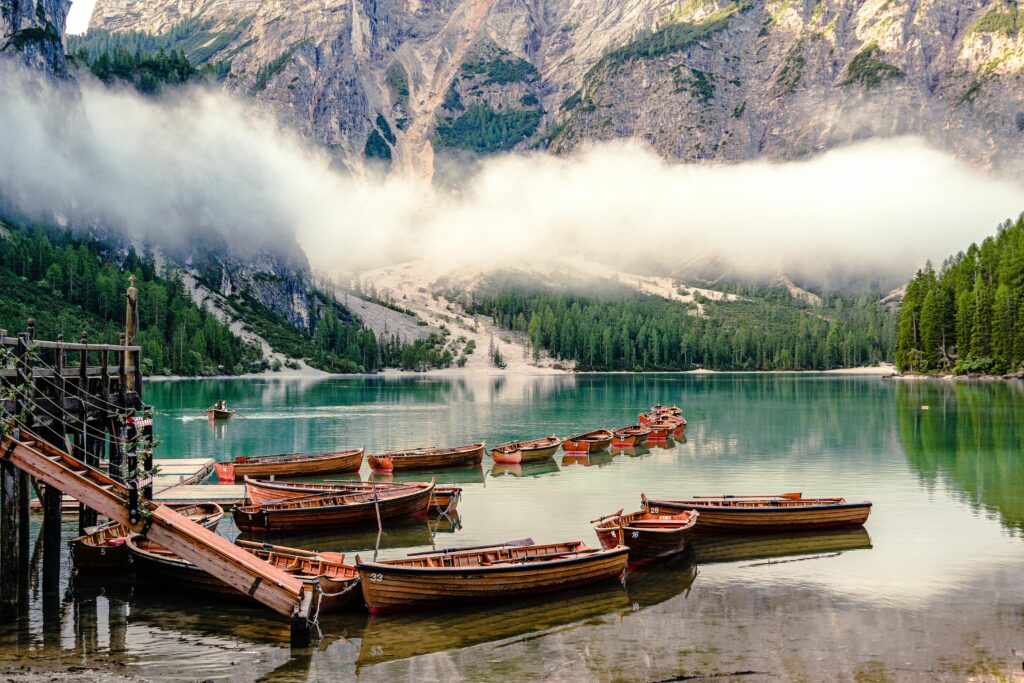 Tranquil scene of wooden boats on Lago di Braies in Trentino-South Tyrol with mountain backdrop.