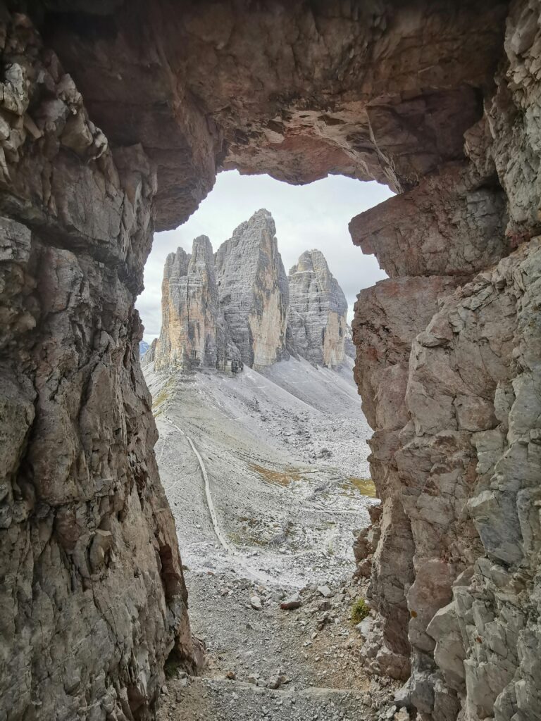 Captivating view of Tre Cime di Lavaredo through rock opening in Dobbiaco, Italy.