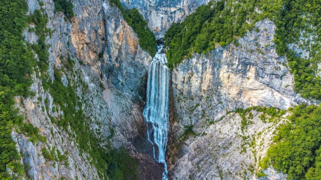 A breathtaking view of a waterfall cascading down a rocky mountain surrounded by lush greenery.